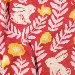 Close-up view of illustrated rabbits and flowers on a knit blanket