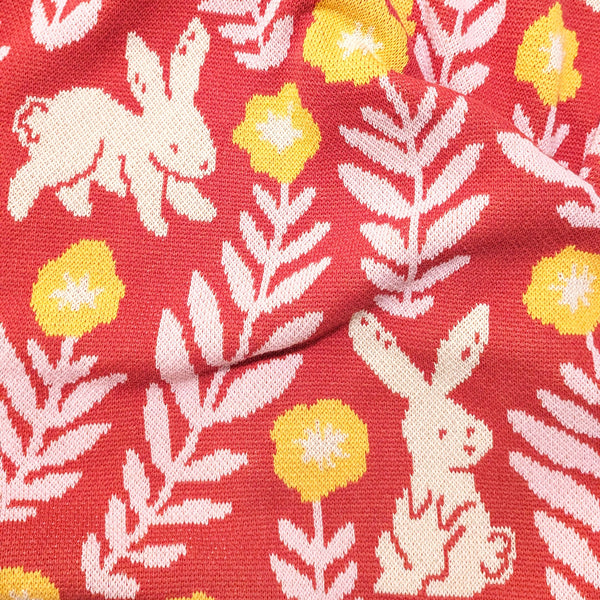 Close-up view of illustrated rabbits and flowers on a knit blanket