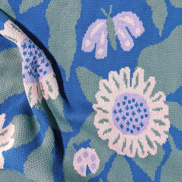 Close-up view of illustrated daisies, butterflies, and ladybugs on a knit blanket