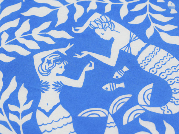 Close up view of two mermaids dancing surrounded by sea leaves and little fish.
